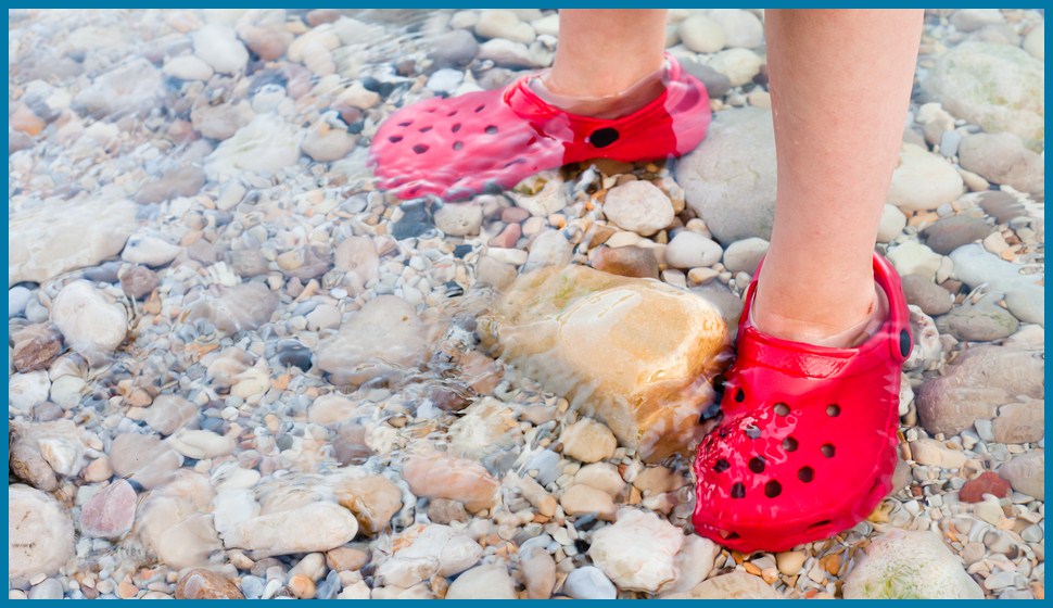 A kid standing in shallow water with crocs alternative clogs